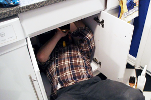 Lowel is under the sink fixing a garbage disposal